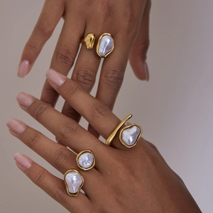 Detail of hand wearing gold irregular fluid rings with baroque pearls for women