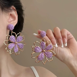 Detail of purple fabric flower earrings with gold hollow frame and silver needles