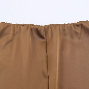 Gros plan de la taille élastique et de la texture soyeuse de la jupe en satin bronze