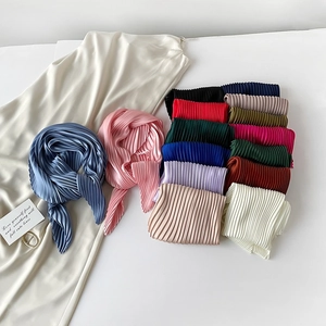 Detailed close-up of pleated silk square scarves in various vibrant colors and textures