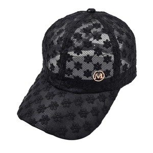 Détail de la casquette de baseball en dentelle noire avec logo M doré élégant