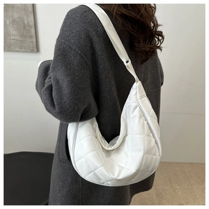 Close-up of white quilted crescent bag with adjustable shoulder strap on female model