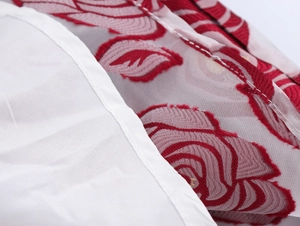 Nahaufnahme von weißem Netzstoff mit roter Blumenstickerei und feiner Nahtführung