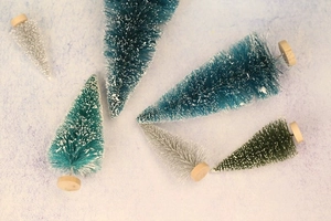 Overhead view of various mini sisal Christmas trees with round wooden bases in assorted colors