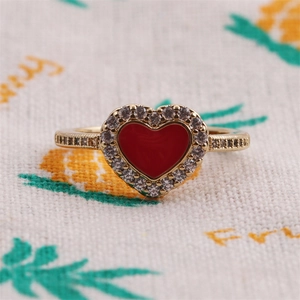 Dettaglio macro di anello a cuore placcato oro con smalto rosso e zircone scintillante