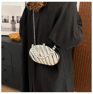 Detail of silver shell-shaped metallic clutch bag with chain strap on a black coat