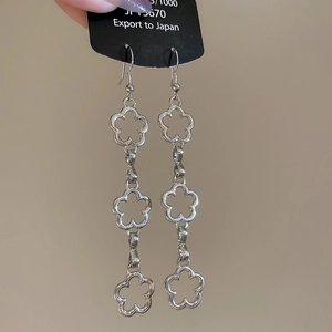 Macro view of long silver hollow flower tassel earrings with intricate metal detailing