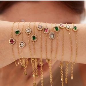 Exquisite gold bracelet set with colorful heart and emerald cut stones on model wrist