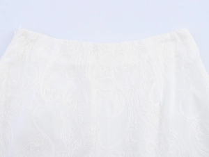 Detail of white shorts featuring intricate paisley embroidery and high-quality lace texture