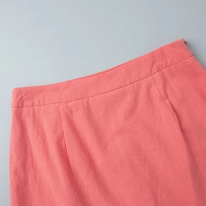 Detail of coral pink cotton skirt waistline featuring fine stitching and linen texture