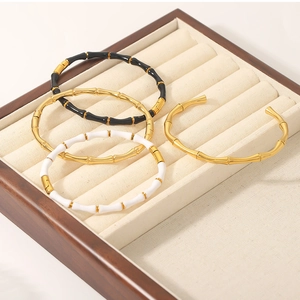 Detail of bamboo joint bangles in gold, black, and white enamel on a wooden tray