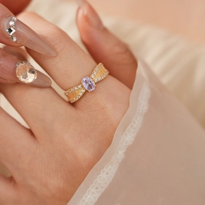 Detailansicht goldener Ring mit lila Stein und Zirkonia im Schleifen-Design