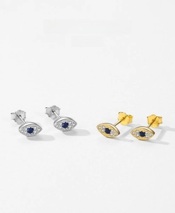Detail of silver and gold Evil Eye stud earrings with blue stones and clear cubic zirconia