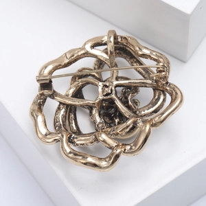 Detailed back view of a hollow flower brooch featuring a secure metal pin and golden finish
