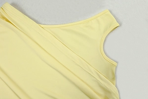 Detail shot of pale yellow knit dress showing shoulder strap and neckline texture