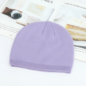 Soft light purple knitted beanie hat with ribbed cuff on a stylish magazine background