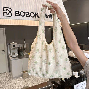 Detail of floral embroidery on cream canvas tote bag with woven shoulder straps