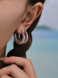 Detailed close-up of silver hoop earrings featuring a unique textured fish scale pattern