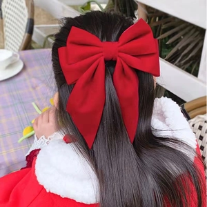 Large red velvet bow hair clip worn by a girl with long dark hair from the back