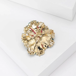 Detail view of the secure pin mechanism on the back of the golden flower brooch