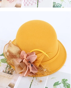 Detail of yellow wool felt hat featuring pink silk flower and decorative mesh veil