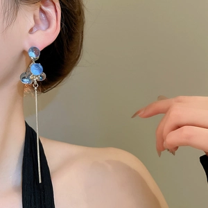 Detail of long drop earrings featuring blue translucent resin beads and silver tassel chains