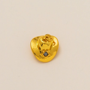 Macro shot of gold cowboy hat pendant featuring a star pattern and a central gemstone