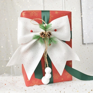 Sparkling white glitter Christmas bow with pine cones and red berries on gift box