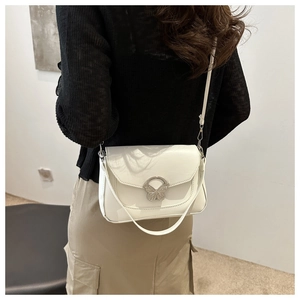 Detail view of a white leather crossbody bag featuring a silver metal butterfly clasp