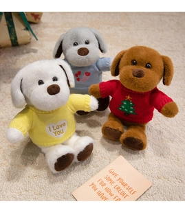 Détail de trois chiots en peluche portant des pulls tricotés sur un tapis doux
