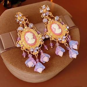 Detail of vintage gold earrings with pink cameo pendants and floral beaded tassels