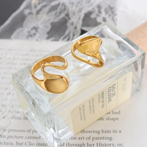 Set of two gold geometric irregular spiral rings displayed on a stylish perfume bottle