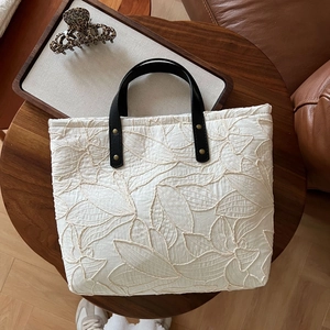 Detail of leaf embroidery on cream canvas tote bag with black leather handle