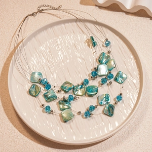 Detail of multi-layered shell and turquoise crystal beads on a silver chain necklace