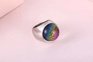 Detailed macro view of an iridescent round glass stone set in a stainless steel ring mount