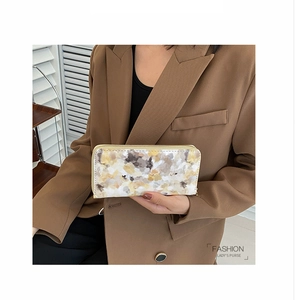Detail of elegant marble pattern women's long wallet with zip closure held by a model