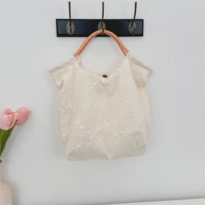 Detail of white floral embroidery on canvas tote with woven orange cord handle