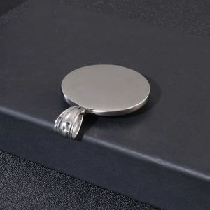 Detailed side view of a thick silver stainless steel compass pendant on a textured base