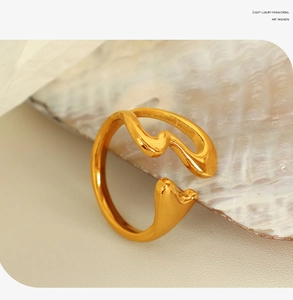 Close-up of golden wavy open heart ring displayed on a natural conch shell