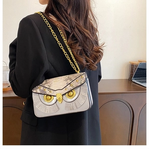 Vue latérale du sac bandoulière hibou avec chaîne dorée porté par un mannequin en intérieur