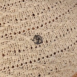Macro view of woven straw bucket hat featuring a vintage silver metal logo with letter D