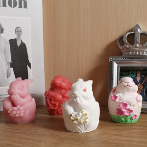 Detail shot of relief flower bunny candle set in four colors on a wooden surface