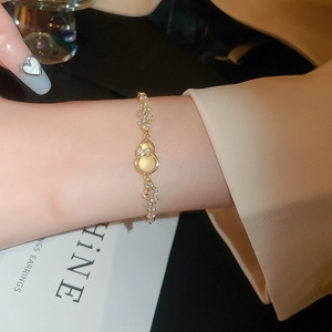 Detail of gold gourd bracelet with cat eye stone and sparkling zircon on woman's wrist