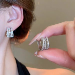 Macro shot of silver layered hoop earrings with cubic zirconia stones showing fit and texture