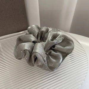 Close-up of silver-grey satin scrunchie featuring elegant rhinestone embellishments