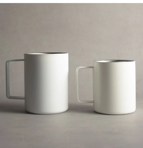 Detail of two white minimalist stainless steel mugs with square handles on grey background