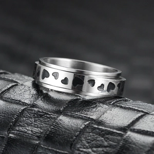 Gros plan d'une bague rotative argentée avec motifs de cœurs noirs sur cuir texturé