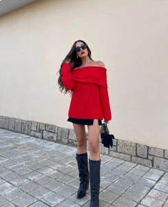 Detail of red off-shoulder knit sweater with long sleeves and visible fabric texture