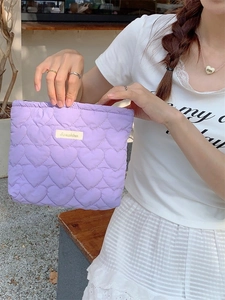 Quilted heart pattern makeup pouch in soft light purple fabric with logo label