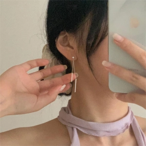 Minimalist long tassel drop earrings in 925 silver finish worn by a model in a mirror selfie